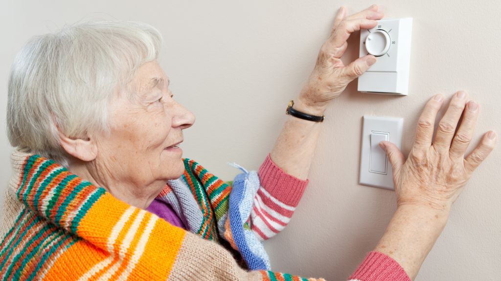 Senior woman adjusting her thermostat