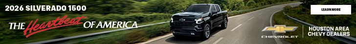 2026 Chevrolet Silverado 1500 pickup truck driving on a road through a wooded area.